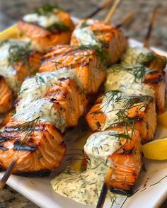 grilled salmon on skewers with sauce and lemon wedges