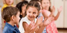 a group of children clapping and standing in front of each other with their hands up