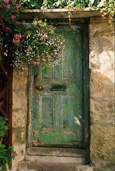 an old green door with flowers growing over it and a quote on the front panel