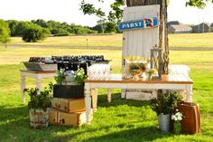 a table with flowers and bottles on it in the grass next to a sign that says oasist