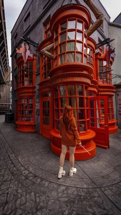 a woman standing in front of a red building with lots of windows and decorations on it