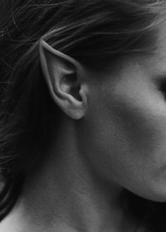 black and white photograph of a woman's face with ear piercings on her ears