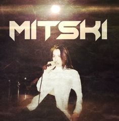 a man standing in front of a microphone on top of a stage with the words mttski above him