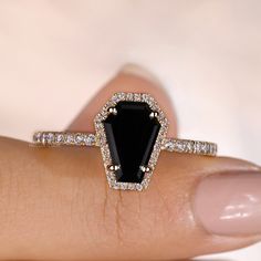 a woman's hand holding a black and white ring with diamonds around it on top of her finger