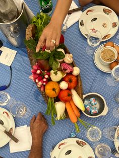 people are gathered around a table with plates, bowls and utensils on it