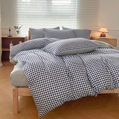 a bed with blue and white checkered comforter on it in front of a window