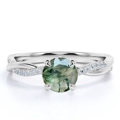 a ring with a green stone and diamonds on the band, set in white gold