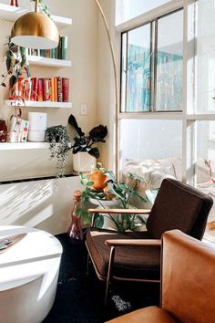 a living room filled with furniture next to a window covered in lots of books and plants