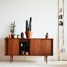 a wooden cabinet filled with potted plants next to a wall mounted planter on top of it