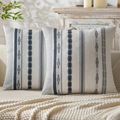 two blue and white pillows sitting on top of a couch next to a potted plant