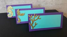 two cards with gold glitter seahorses on purple and blue paper, one has a green background