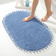 a person standing on top of a blue rug in front of a bathtub and toilet