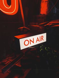 an on air sign sitting in front of a red neon sign that says on air