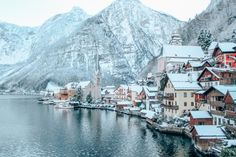 the snow covered mountains are in the background and houses along the water's edge