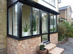 a brick house with black windows and plants in the window sill on either side