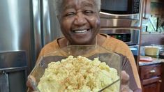 an older woman holding up a bowl of food in her hands and smiling at the camera