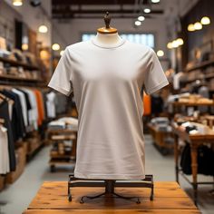 a white t - shirt on a wooden stand in a store with lots of clothes