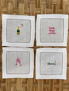 three embroidered napkins with words on them sitting on a wicker tablecloth background