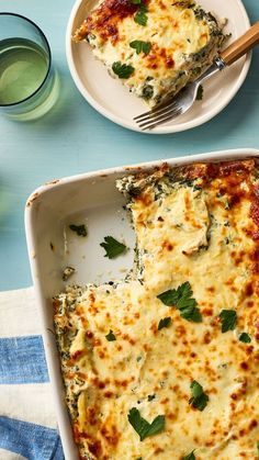 a casserole dish with spinach and cheese on it next to a glass of water