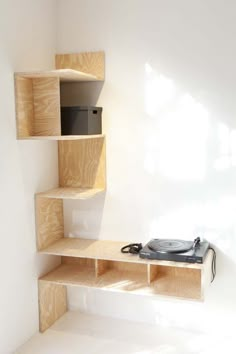 a record player sitting on top of a wooden shelf next to a wall mounted speaker