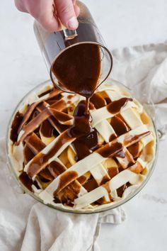 someone pouring chocolate sauce on top of a pie