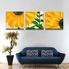 three yellow sunflowers are hanging on the wall above a blue couch in a living room