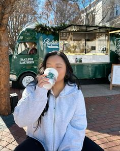 a woman sitting on the ground drinking from a cup