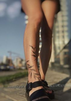 a woman's legs with tattoos on them walking down the sidewalk in sandals and heels