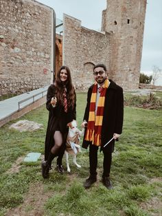 a man and woman pose with their dog in front of an old castle like building