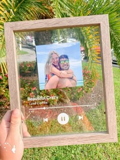 a person holding up a wooden frame with a photo on it