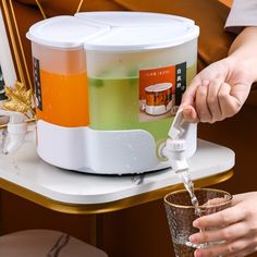 a person pouring liquid into a glass on top of a table with an orange and white container