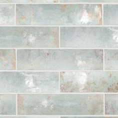 a white and grey brick wall with rusted metal foil on the bottom half of it