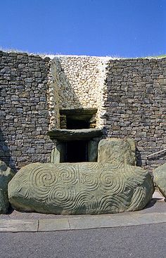 a stone sculpture sitting on the side of a road next to a building with a doorway