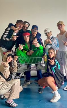 a group of people posing for a photo with a shopping cart in front of them