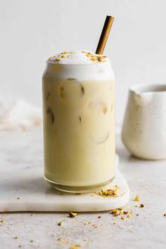 an iced drink with whipped cream and cinnamon sticks in the top is sitting on a white surface