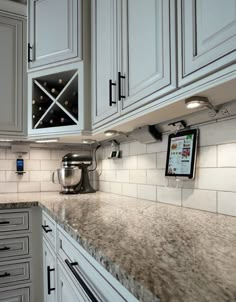 a kitchen with white cabinets and granite counter tops, wine rack on the wall in the corner