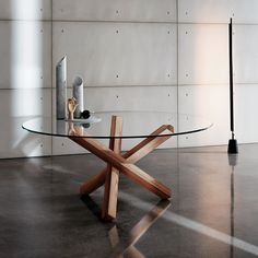 a glass table with wooden cross legs in an empty room