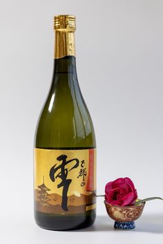 a bottle of sake with a rose next to it