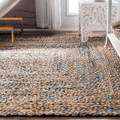 an area rug with blue and tan colors in a room next to a window,