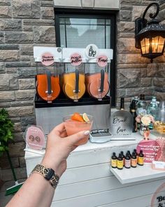 a person holding up a drink in front of a counter with bottles and glasses on it