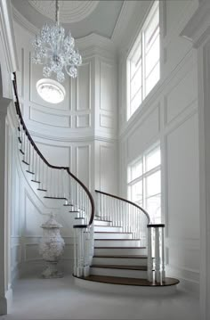 an elegant staircase with chandelier and white walls