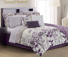 a bed with purple and white comforters in a room