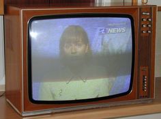 an old television set with the news on it's screen and a person behind it