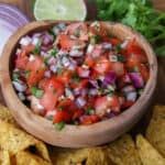 a wooden bowl filled with salsa next to tortilla chips