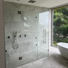 a bathroom with a tub, shower and large glass window overlooking the trees in the background