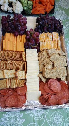 an assortment of cheeses, crackers and vegetables on a tray