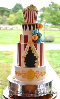 a three tiered cake is decorated with colorful decorations and popcorn cones on top of it