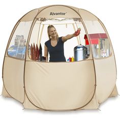 a woman standing in front of a tent with the door open and shelves full of items