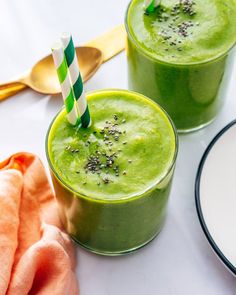 two glasses filled with green smoothie on top of a table