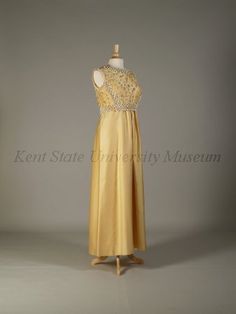 Pierre Balmain Haute Couture evening dress from French 1960-1970. Made from yellow silk satin peau de soie ground, yellow dome caps, embroidered  embroidery with bead, pearl, rhinestones, cream cord loops, white plastic lilies flower, light yellow braid trim,  and dome lucite button. Sleeveless floor length A line gown in scoop necked style.#Balmain #HauteCouture #Vintage #Fashion House of Balmain. Yellow Evening Dress, Yellow Silk